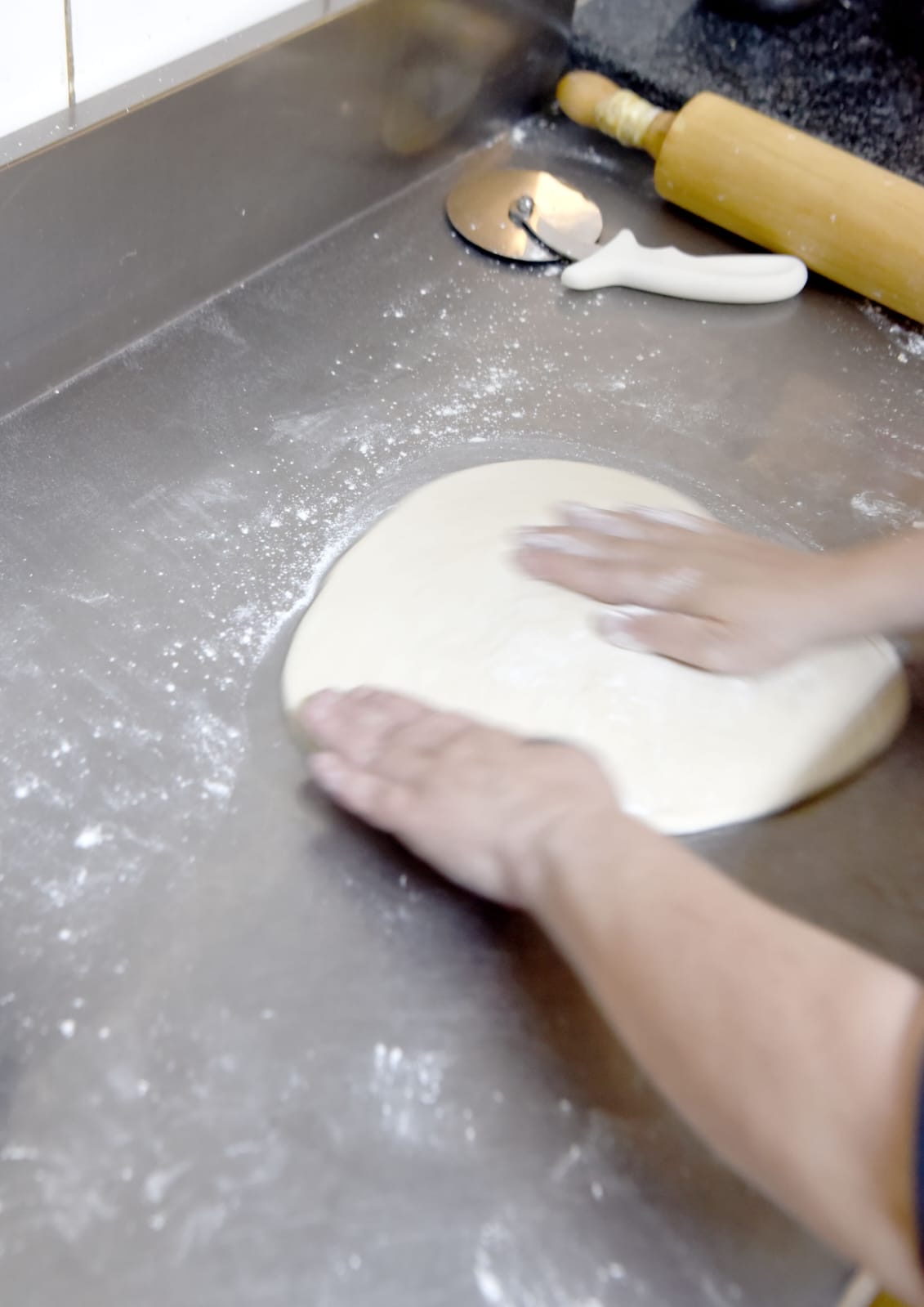 Pressing pizza dough by hand